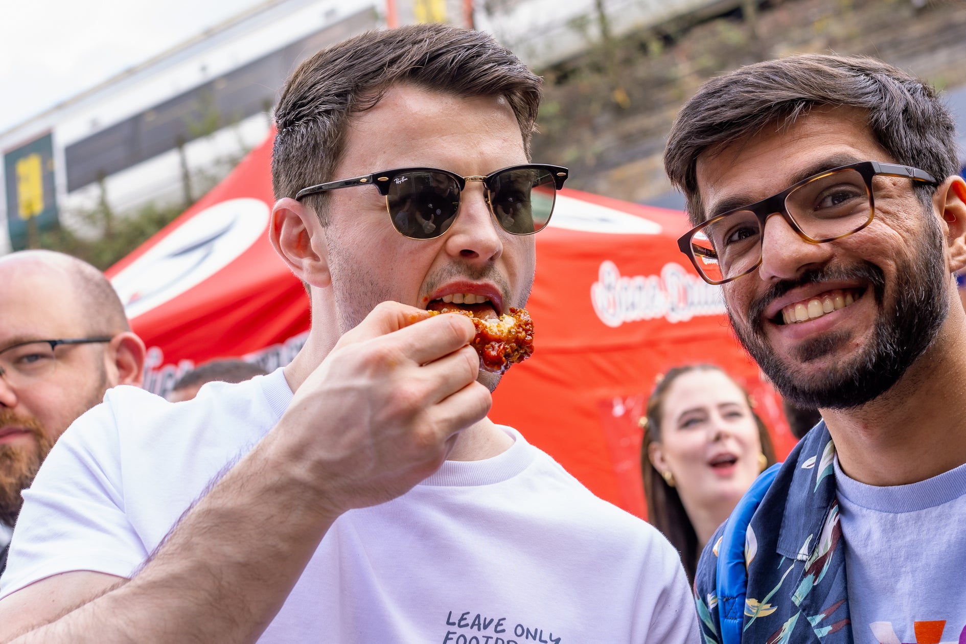a guy bites a chicken wing at wingjam, WingJam London Friends Relishing Every Wing Bite Together, WingJam London A Celebration of Great Wings and Good Friends, WingJam London The Ultimate Gathering for Chicken Wing Fans, WingJam London Where Friends Enjoy the Best Chicken Wings in London